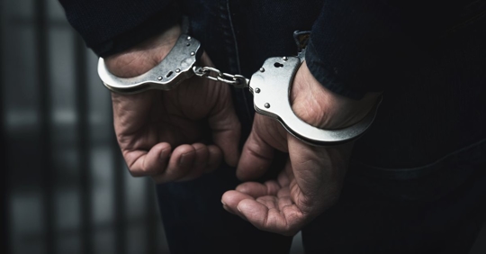 man with hands cuffed behind his back
