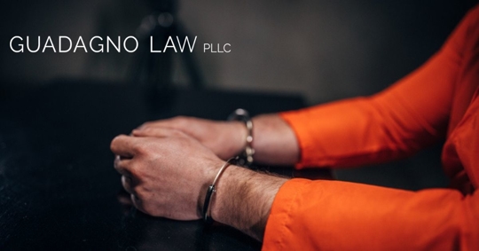 Prisoner in orange jumpsuit with handcuffs sitting in the investigation room